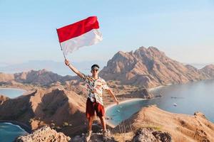 Indonesische toerist die met trots de Indonesische vlag op de top van de berg bij Labuan Bajo zwaait of hijst foto