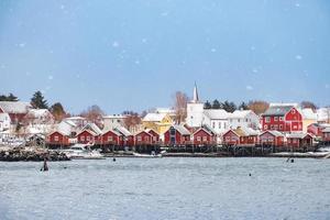 vissersdorp met christelijke kerk in reine town aan de kust in sneeuwdag op de lofoten-eilanden foto