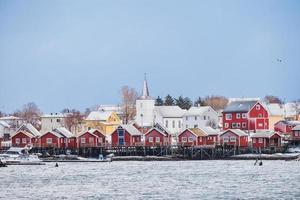 vissersdorp met christelijke kerk in reine town aan de kust in sneeuwdag op de lofoten-eilanden foto