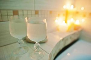 twee natte glazen wijn achtergrond brandende kaarsen in badkamer foto