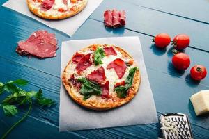 bovenaanzicht van pizza over trendy blauwe houten vintage achtergrond met pizza-ingrediënten. foto