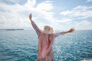 gelukkige vrouw met een zomerhoed die geniet van de zomervakantie met een prachtig zeegezicht op het eiland Karimun Jawa foto