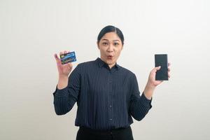Aziatische vrouw die smartphone gebruikt met de hand met creditcard foto