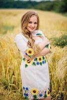jong meisje op Oekraïense nationale klederdracht gesteld op krans veld. foto