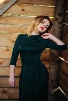 yong elegantie blond meisje op groene jurk achtergrond houten structuur. foto