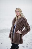 portret van jonge elegantie blond meisje in een bontjas achtergrond mistige rivier op winterijs. foto