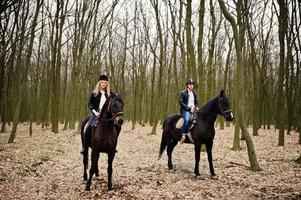 jonge stijlvolle paar rijden op paarden in herfst bos. foto