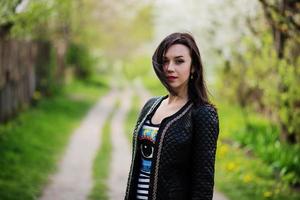 brunette meisje op leren jas gesteld op lentetuin. foto