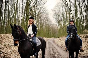 jonge stijlvolle paar rijden op paarden in herfst bos. foto