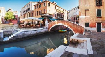 traditionele gondels op smal kanaal tussen kleurrijke historische huizen in Venetië, Italië foto