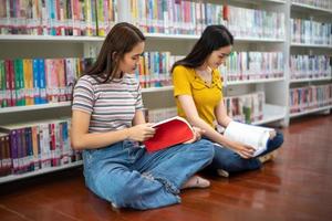 groep Aziatische studenten glimlachen en lezen een boek en gebruiken een notebook om ideeën in het werk en project te delen. en bekijk ook het boek voor het examen foto