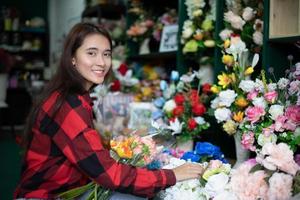 lachende vrouw bloemist klein bedrijf bloemenwinkel eigenaar en jonge bloemist die bloemen in de winkel onderzoekt foto