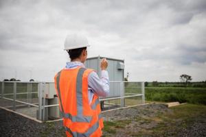 Aziatische ingenieur met veiligheidshelm met behulp van tablet pc-computer inspecteren en werken bij windturbinepark stroomgeneratorstation foto