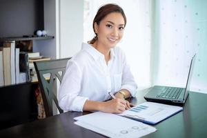 mooie Aziatische zakenvrouwen die documenten controleren en een notitieboekje gebruiken om thuis te werken foto