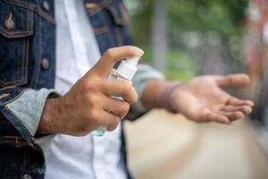 Aziatische mannen die alcoholspray en alcoholgel of lotion gebruiken om griep en viruspreventie bij de hand te hebben foto