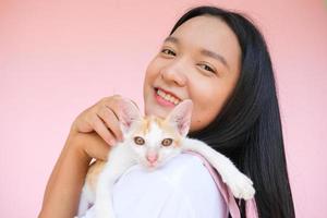 glimlach jong meisje met kat op roze achtergrond. foto