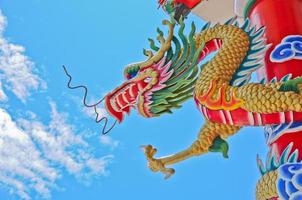 gouden vliegende majestueuze Aziatische Chinese draak standbeeld met blauwe lucht in zonnige dag foto