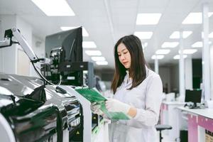 jonge vrouwelijke wetenschapper let op de resultaten van het automatiseringsbloedanalysatorrapport in medisch laboratorium foto