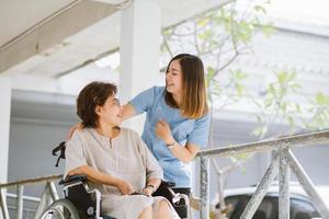 lachende fysiotherapeut die voor de gelukkige senior patiënt in rolstoel zorgt foto