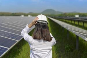 vrouwelijke ingenieur met helm in fotovoltaïsche celboerderij of zonnepanelenveld, milieuvriendelijke en schone energie. foto