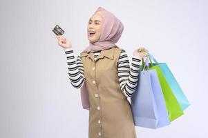 jonge mooie moslimvrouw in pak met kleurrijke boodschappentassen op een witte achtergrond studio foto