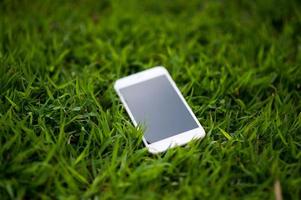 mobiele telefoon geplaatst in een lichtgroen gras. elke telefoon moet een huis hebben. telefoon concept foto