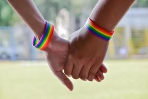 regenboog rubberen polsbandjes in de polsen van een aziatisch jongenspaar met onscherpe achtergrond, concept voor de viering van de lgbt-gemeenschap in de trotsmaand of in juni over de hele wereld. foto