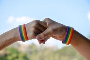 regenboog rubberen polsbandjes in de polsen van een aziatisch jongenspaar met onscherpe achtergrond, concept voor de viering van de lgbt-gemeenschap in de trotsmaand of in juni over de hele wereld. foto