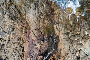 luchtfoto van boven naar beneden van kustgolven en rotsachtige kustweergave stenen rotsen textuur natuurlijke achtergrond foto