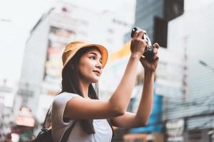 jonge aziatische vrouw met instant camera in bangkok, thailand foto