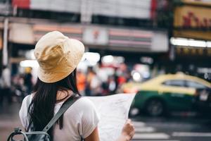 jonge volwassen aziatische vrouw die kaart gebruikt tijdens het reizen in yaowarat china town. foto