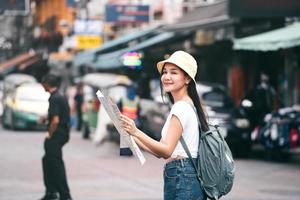 jonge volwassen aziatische reiziger verken de zoekkaart tijdens het bezoeken van bezienswaardigheden. bij landmark khaosan foto