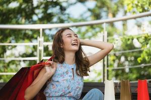 Aziatische jonge vrouw shopper zit en glimlach foto