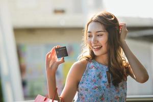 Aziatische jonge vrouw winkelen betalen met creditcard. foto