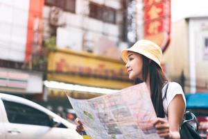 volwassen aziatische vrouw die kaart gebruikt voor solo-reisrugzak in bangkok. foto