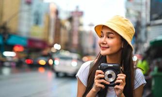 Aziatische reiziger vrouw houdt instant camera vast foto