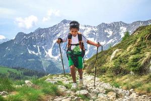 kleine jongen loopt tijdens een excursie op het bergpad met de rugzak foto
