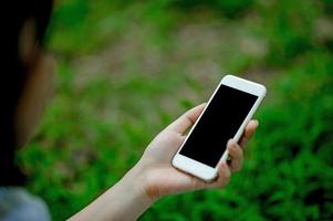 meisje dat telefoon speelt voor online communicatie en contact draagt een rood shirt en een groene achtergrond en er is een kopieerruimte. foto