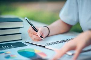 vrouw zit aan bureau en werkt bij de hand van boek en financiële documenten close-up foto