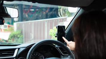 de vrouw stopte haar smartphone in de autotelefoonhouder voor de reis en gebruikte de gps-kaart. foto