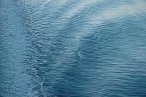 witte backwash van een veerboot die de blauwe oceaan oversteekt foto