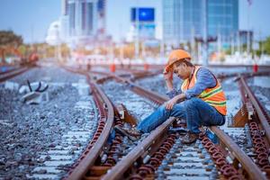 ingenieur spoorweg onder controle bouwproces trein testen en controleren van spoorwegwerkzaamheden op het treinstation met radiocommunicatie. ingenieur met veiligheidsuniform en veiligheidshelm op het werk. foto