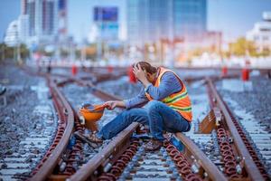 ingenieur spoorweg onder controle bouwproces trein testen en controleren van spoorwegwerkzaamheden op het treinstation met radiocommunicatie. ingenieur met veiligheidsuniform en veiligheidshelm op het werk. foto