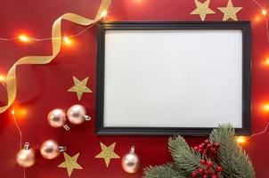 Kerst achtergrond met frame mockup, glinsterende sterren, gouden lint en ornamenten op rode achtergrond.