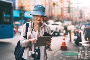 jonge volwassen aziatische vrouwenreiziger die alleen reist met moderne leer met behulp van tablet. foto