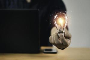 zakenman hand met gloeilamp met gloeiend licht tot creatief slim denken voor inspiratie en innovatie met netwerkconcept. foto