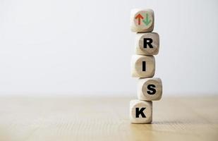 risicoformulering en pijl omhoog naar beneden printscherm houten kubusblok voor risicobeheerconcept. foto