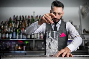 barman die cocktail in glas mengt foto