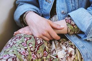 middengedeelte van een jonge vrouw die een spijkerjasje draagt over een zomerjurk met bloemmotief foto