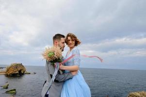 bruiloft fotosessie van een paar aan de kust. blauwe trouwjurk op de bruid. foto